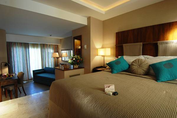 Schlafzimmer im Marti Resort Hotel mit einem großen Bett, blauen Kissen und einer Tischlampe.