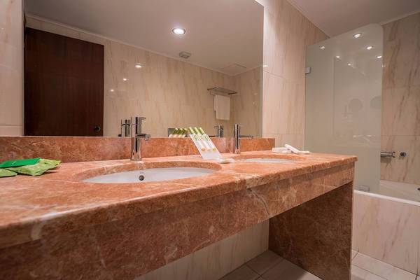 Badezimmer im Galaxy Beach Resort mit Marmorwaschtischen, Spiegel und Badewanne.