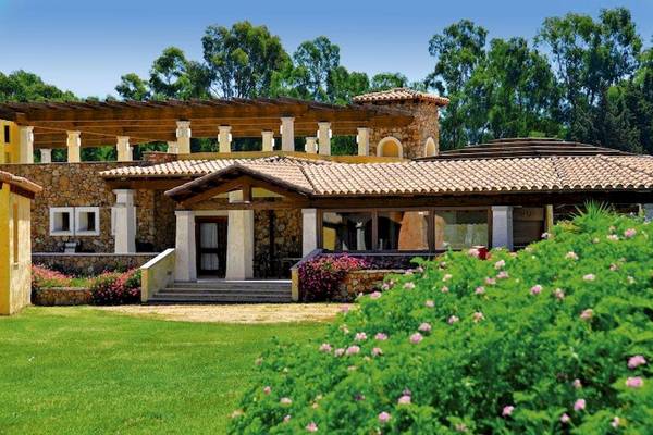 Außenansicht des Limone Beach Resorts mit Steinmauer, Holzdach und Garten