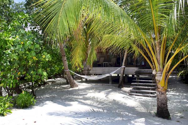 Ein kleines Haus auf Stelzen mit einer Hängematte vor Gangehi Island Resort.