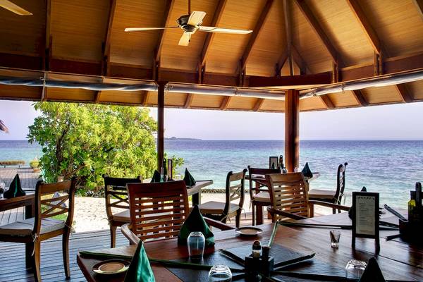 Außenbereich des Gangehi Island Resort mit Blick auf das Meer und einen bestuhlten Tisch