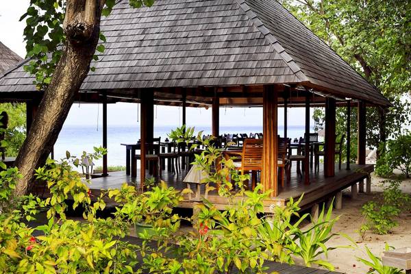 Außenterrasse des Gangehi Island Resorts mit Blick auf das Meer und gesäumt von Pflanzen.