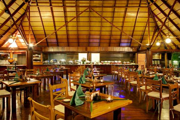 Innenansicht des Restaurants im Gangehi Island Resort mit gedeckten Tischen und dekorativen Kerzen.