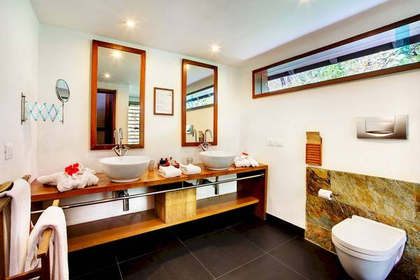 Badezimmer des Gangehi Island Resorts mit zwei Waschbecken, Spiegeln und einer Toilette.