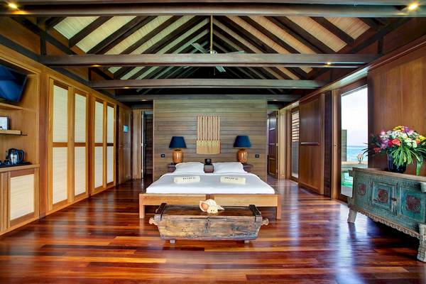 Schlafzimmer im Gangehi Island Resort mit zwei Betten, Lampen und Holzmöbeln.