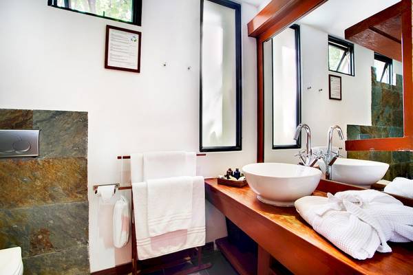 Badezimmer im Gangehi Island Resort mit weißen Handtüchern, Waschbecken und Spiegel.