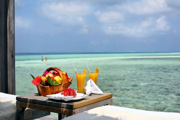 Früchte und Getränke auf einer Terrasse des Gangehi Island Resorts mit Blick auf das Meer.