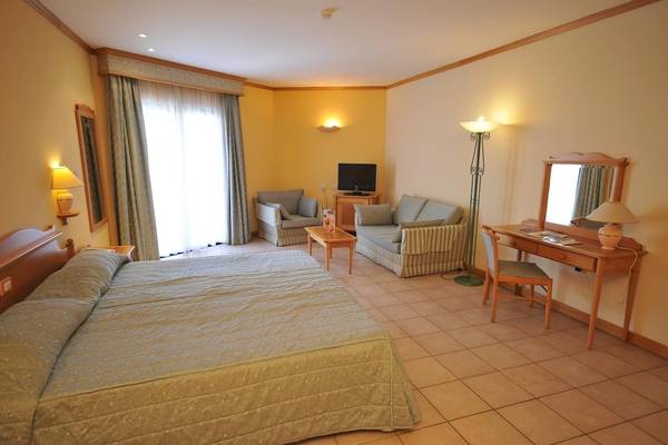 Innenansicht eines Zimmers im Grand Hotel Gozo mit Bett, Möbeln und Fernseher.