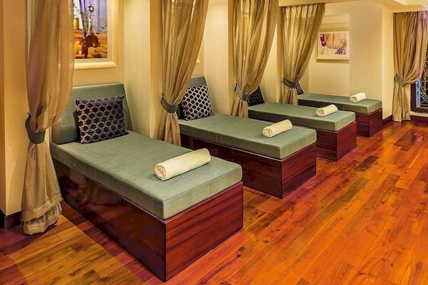 Spa-Lounge im Grand Hotel Gozo mit grünen Liegen, Holzböden und Kerzen.