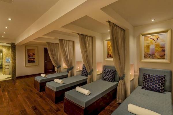 Behandlungsraum im Grand Hotel Gozo Spa mit drei Liegen, Kissen und Vorhängen.