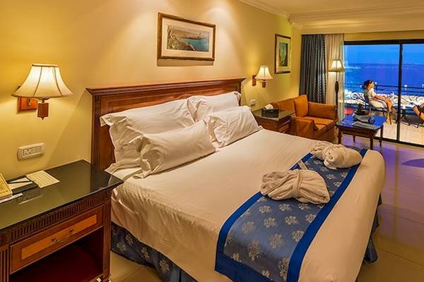 Ein Hotelzimmer im Grand Hotel Gozo mit einem großen Bett, Fenstern und einem Blick auf das Meer.