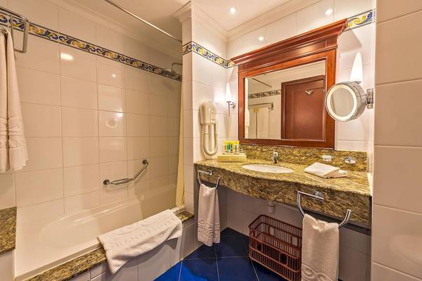 Badezimmer im Grand Hotel Gozo mit Badewanne, Waschbecken und Spiegel.