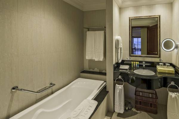 Badezimmer im Grand Hotel Gozo mit Badewanne, Waschbecken und Spiegeln.