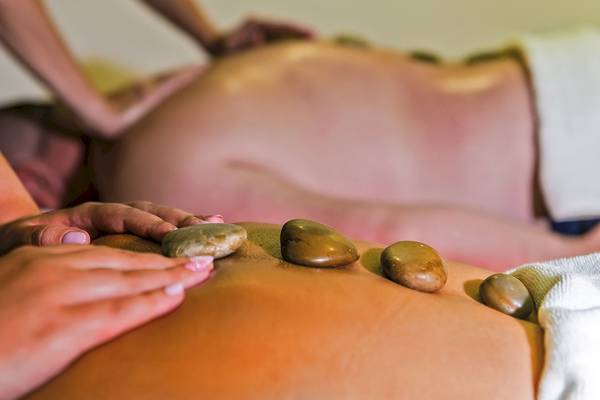 Eine Person, die eine Rückenmassage mit Steinen im Grand Hotel Gozo genießt.