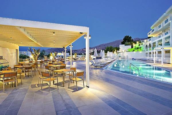 Außenbereich des Lindos White Hotel & Suites mit Terrasse, Tischen, Stühlen und Swimmingpool.