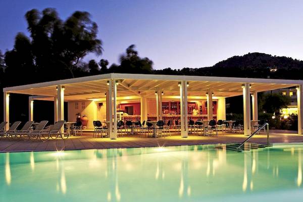 Abendstimmung am Pool des Lindos White Hotel & Suites mit einer überdachten Terrasse und Tischen.