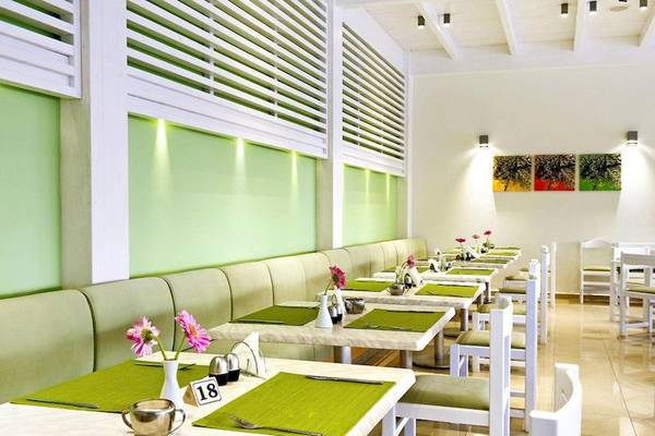 Innenansicht des Restaurants im Lindos White Hotel & Suites mit grünen Wänden und weißen Möbeln.