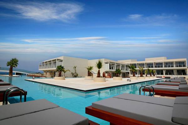 Poolbereich des Insula Alba Resort & Spa mit weißen Gebäuden und Sonnenliegen