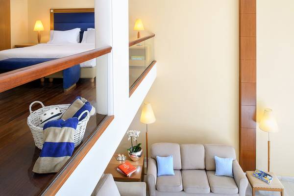Suite im Mitsis Lindos Memories Resort & Spa mit Blick auf ein Doppelbett und Wohnzimmer.