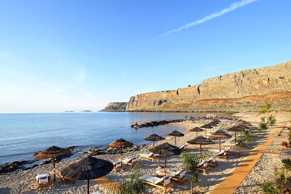 Strand des Mitsis Lindos Memories Resort & Spa mit Sonnenliegen und Sonnenschirmen