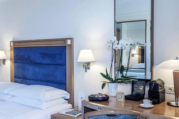 Hotelzimmer im Mitsis Lindos Memories Resort & Spa mit Bett, Schreibtisch, Blumen und Kaffeemaschine.