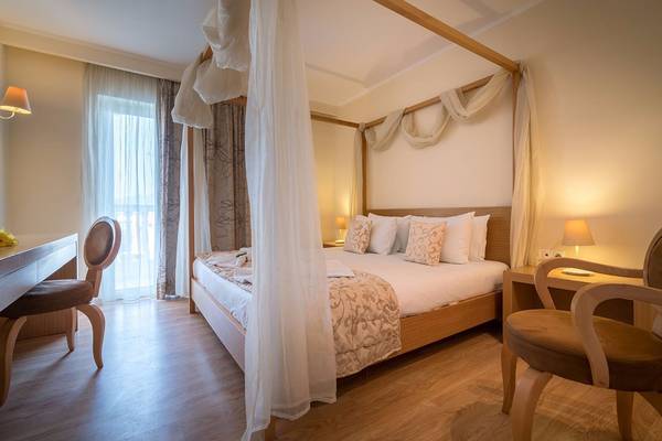 Hotelzimmer im Galaxy Beach Resort mit Himmelbett, zwei Nachttischen und Stühlen.