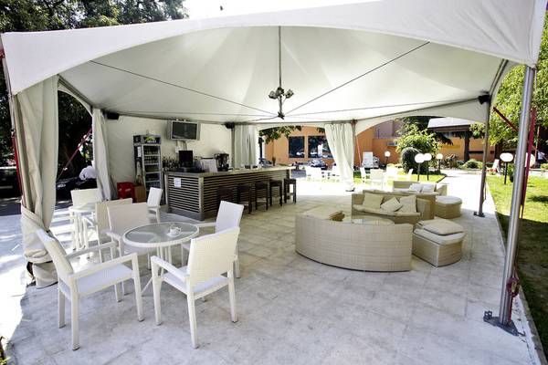 Terrasse des Gladiola Star Hotels mit weißen Möbeln, Bar und Schirm.