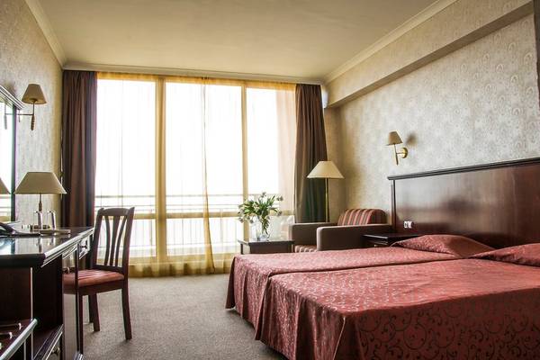 Doppelzimmer im Gladiola Star Hotel mit zwei Betten, Schreibtisch und Fenstern.