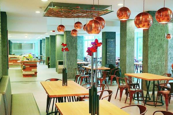 Innenbereich des Gladiola Star Hotels mit runden Kupferlampen und grünen Säulen.
