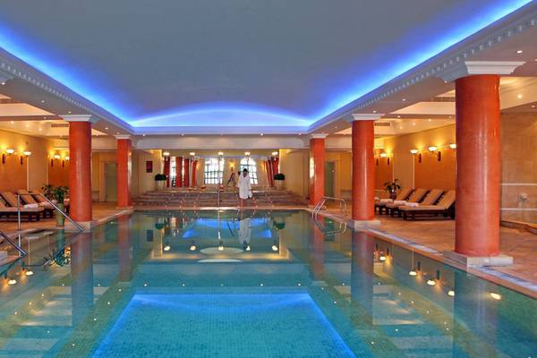 Innenpool im Elysium Hotel mit orangefarbenen Säulen und blauer Beleuchtung.