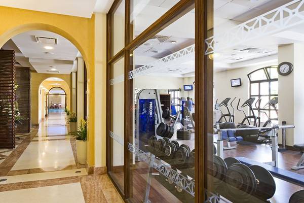 Korridor im Fitnesscenter des Elysium Hotels mit Blick auf Trainingsgeräte und eine Schwimmhalle.
