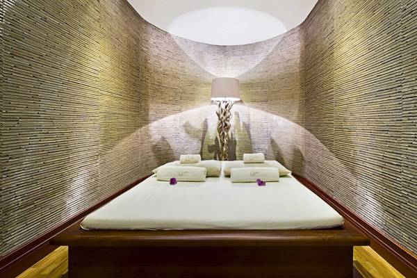 Spa-Behandlungsraum im Elysium Hotel mit Bett, Kissen und Lampe.
