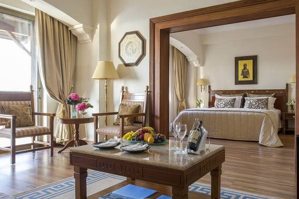 Innenansicht eines Schlafzimmers im Elysium Hotel mit Bett, Tisch, Stühlen und Dekoration.