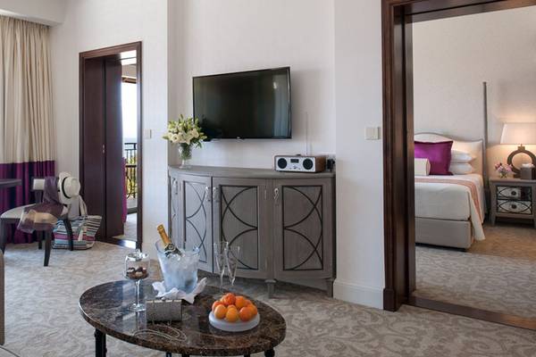 Innenansicht der Suite im Elysium Hotel mit Fernseher, Tisch und Bett.