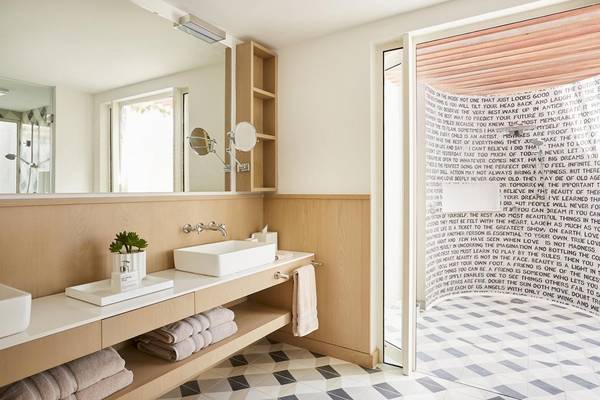 Badezimmer im LUX Grand Gaube Resort & Villas mit heller Beleuchtung, modernen Möbeln und einer Wand mit Text.