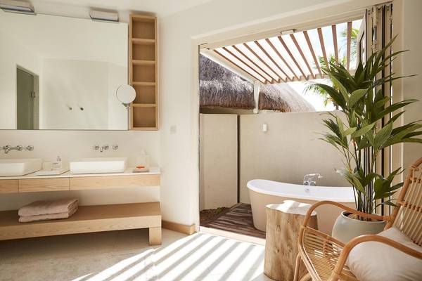 Badezimmer im LUX Grand Gaube Resort & Villas mit Badewanne, Waschbecken und Pflanzen.