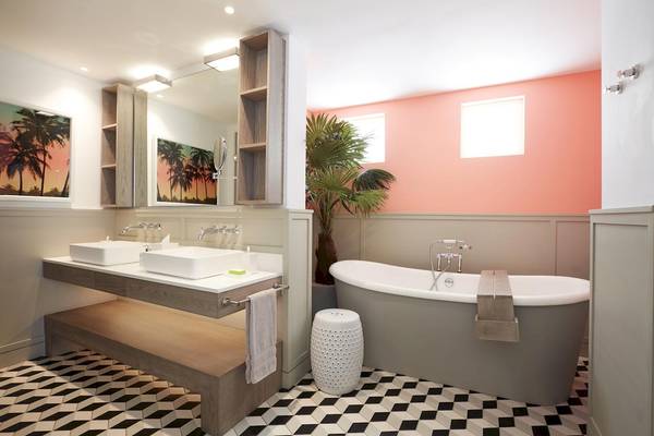 Badezimmer im LUX Grand Gaube Resort & Villas mit zwei Waschbecken, Badewanne und tropischer Pflanze.