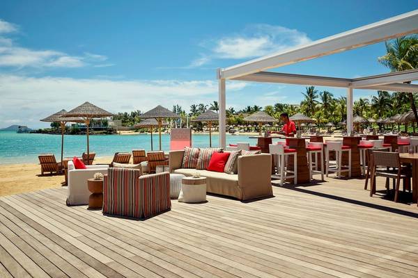 Lux Grand Gaube Resort & Villas Strandlounge mit Möbeln, Sonnenschirmen und Blick auf das Meer.