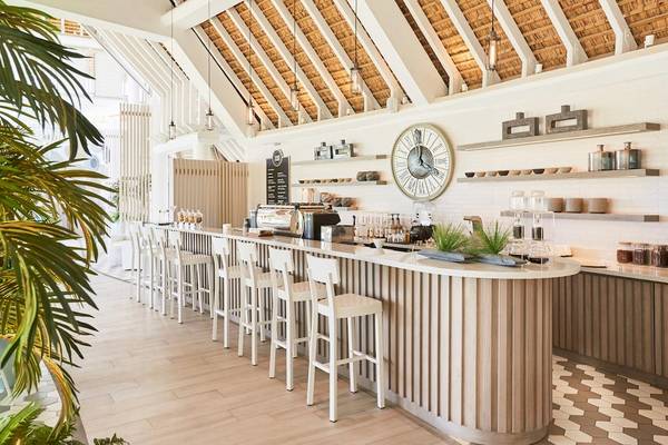 Innenansicht der Rezeption des LUX Grand Gaube Resort & Villas mit Bar, Uhr und Pflanzen.