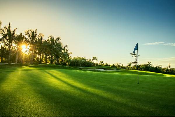 Golfplatz im LUX Grand Gaube Resort bei Sonnenuntergang mit Flagge und Palmen