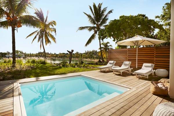 Luxuriöse Poolterrasse im LUX Grand Gaube Resort & Villas mit weißen Liegen und Sonnenschirm.