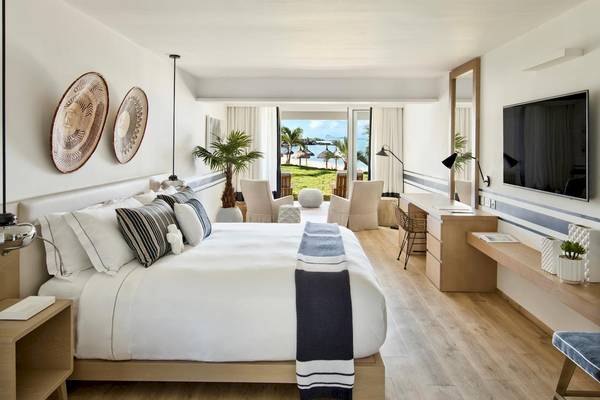Lux Grand Gaube Resort & Villas Schlafzimmer mit Meerblick, weiße Möbel und Holzboden.
