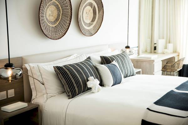 Lux Grand Gaube Resort & Villas Schlafzimmer mit weißen Bett, Kissen, und Dekor an der Wand.