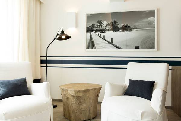 Wohnzimmer im LUX Grand Gaube Resort & Villas mit zwei weißen Sesseln, einem Holztisch und einer Fototapete.