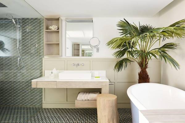 Ein Badezimmer im LUX Grand Gaube Resort & Villas mit einer Badewanne, einem Waschbecken und einer Palme.