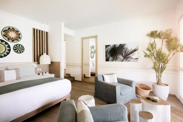 Lux Grand Gaube Resort & Villas Schlafzimmer mit Bett, Stühle, Pflanze und Wanddekoration