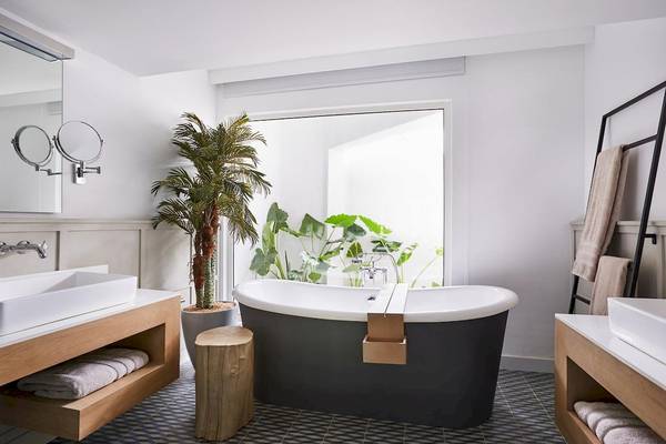 Badezimmer im LUX Grand Gaube Resort & Villas mit Badewanne, Waschbecken, Spiegel und Pflanzen.