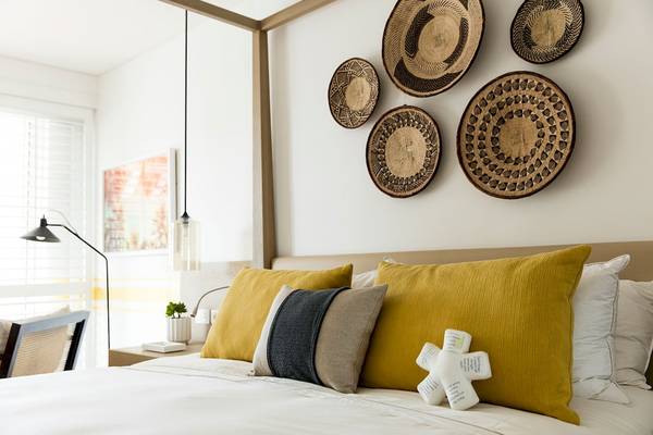 Ein luxuriöses Schlafzimmer im LUX Grand Gaube Resort & Villas mit einem Bett, dekorativen Kissen und Wandkörben.