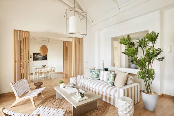 Wohnzimmer im LUX Grand Gaube Resort & Villas mit weißem Sofa, Holzboden und großen Pflanzen.