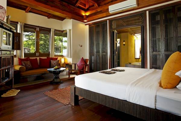 Schlafzimmer im Moracea by Khao Lak Resort mit Holzboden, Bett, Sofa und Fenstern.